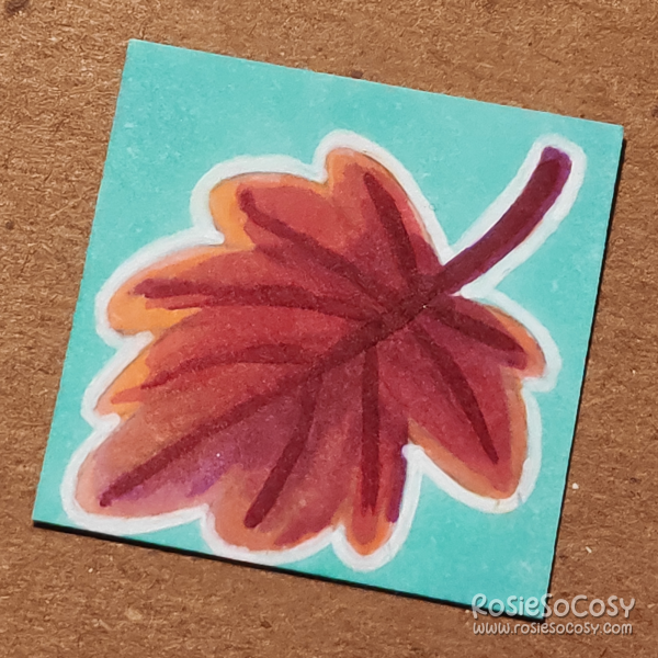 An inch sized drawing of a red maple leaf.