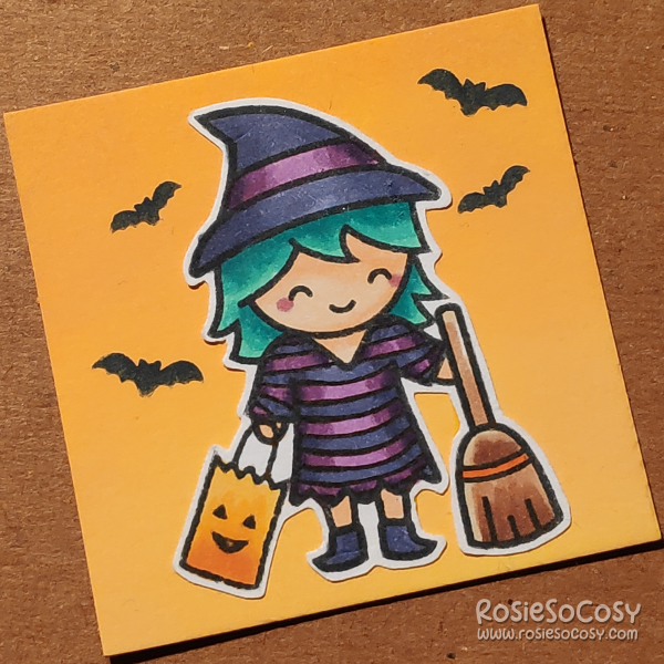 A tiny 2 inch card with a cute witch (actually a child dressed up as a witch for Halloween). She is wearing a purple striped tunic/dress, blueish grey witch's boots and a matching witch's hat. She is carrying a trick or treat bag in her right hand, and a brown broom in her left. Around her are four bats. She has a light skin tone and seafoam hair. The background of the card is yellow.