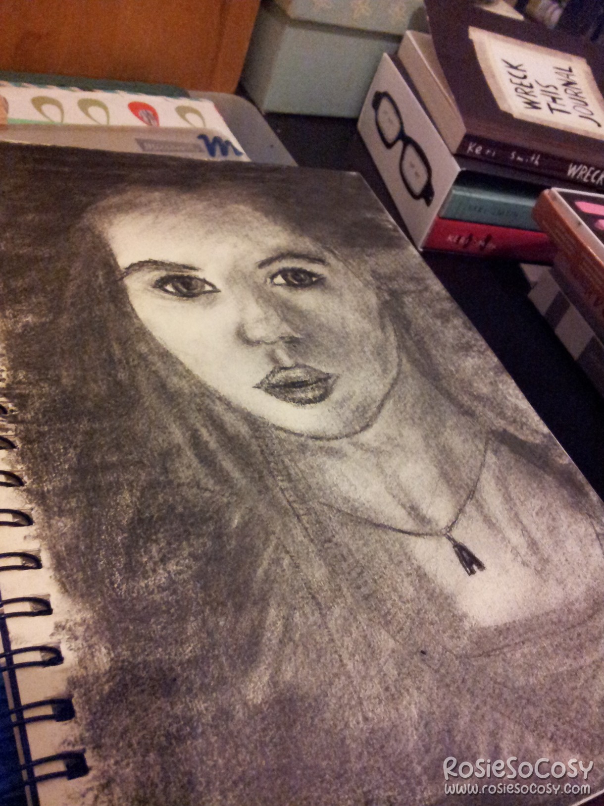 A charcoal drawing of Amy Pond (portrayed by Karen Gillan) in Doctor Who. Amy is looking at the camera. She has big eyes and somewhat pouted lips. She is wearing a necklace with the letter A on it.