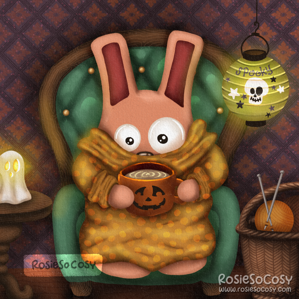 It’s an illustration of a pink Freezer Bunny with dark pink ears. Freezer Bunny is wearing an ochre yellow dotted snuggly blanket type sweater, holding an orange pumpkin mug with what looks like a latte. Freezer Bunny is seated on a teal coloured armchair with a diamond tuffed pattern on the back, and a wooden frame and legs. On the left is a round end table with a ghost candle holder. On the right is a wicker basket on the floor with little balls of yarn and knitting needles.