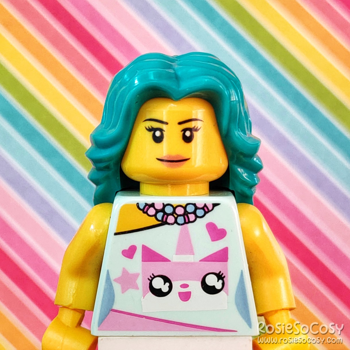 Rosie's Minifig with Unikitty Outfit with a diagonal rainbow striped background.